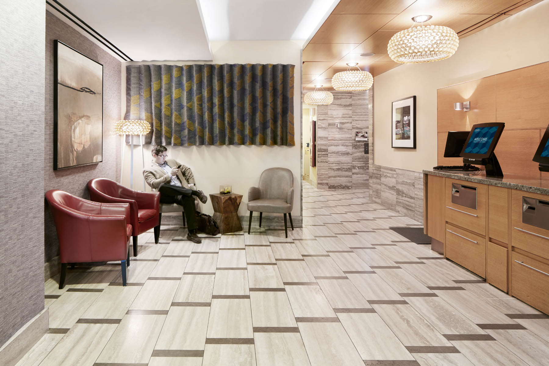 A hotel lobby with a reception desk, seating area, and chandeliers.