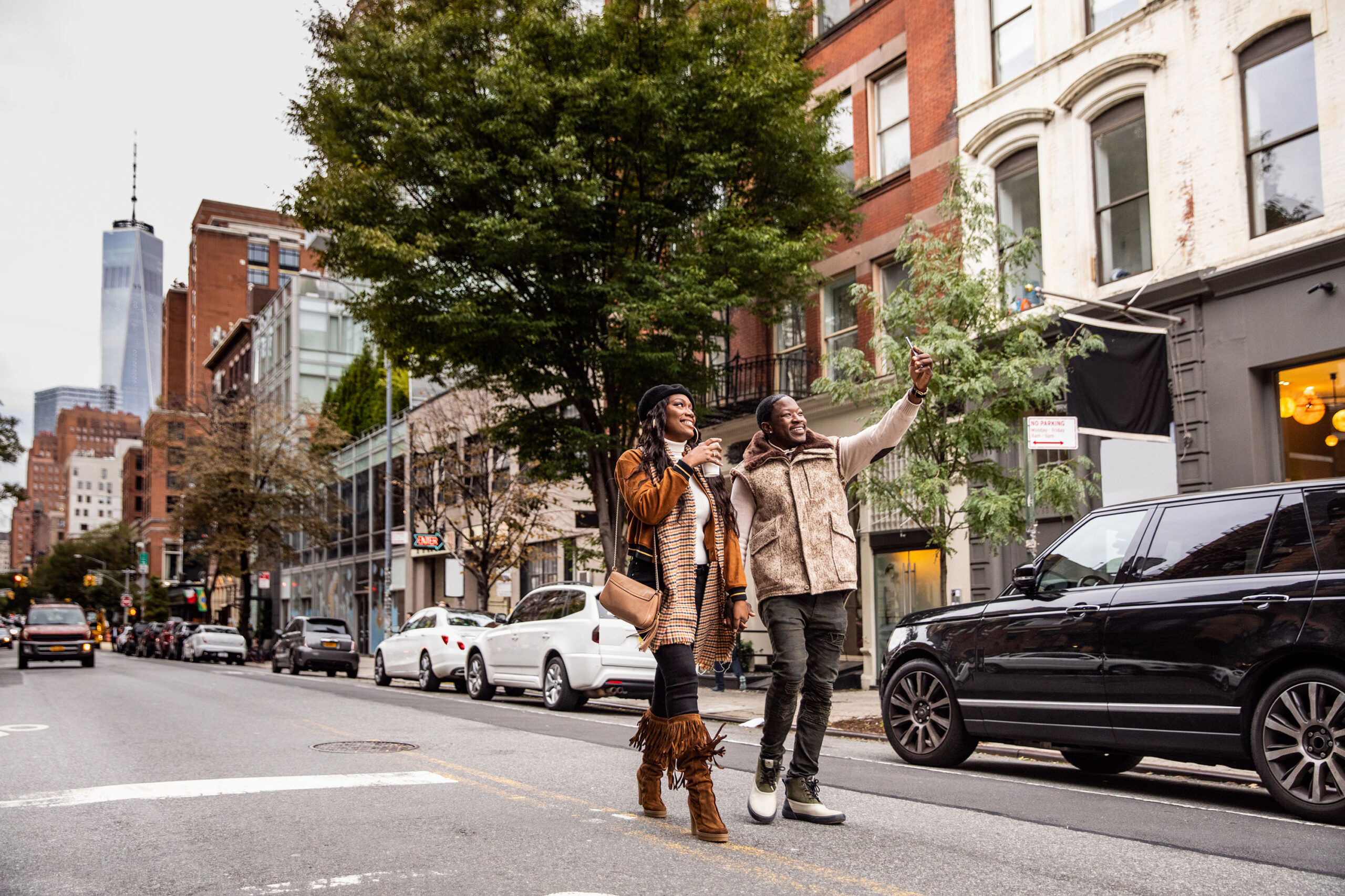 A street scene with a couple in the foreground and city buildings in the background.
